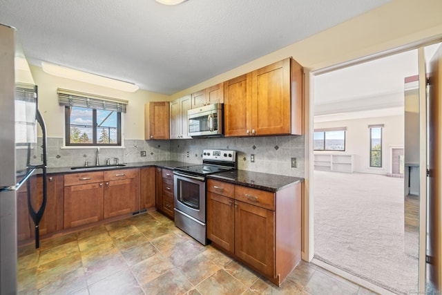 kitchen with decorative backsplash, a sink, stainless steel appliances, and light carpet