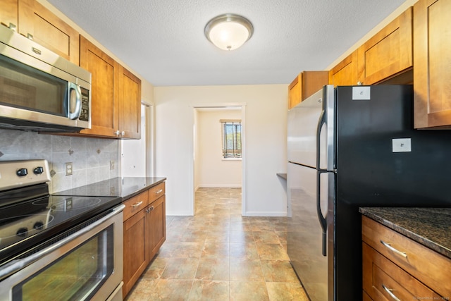 kitchen featuring brown cabinets, tasteful backsplash, dark stone countertops, and stainless steel appliances
