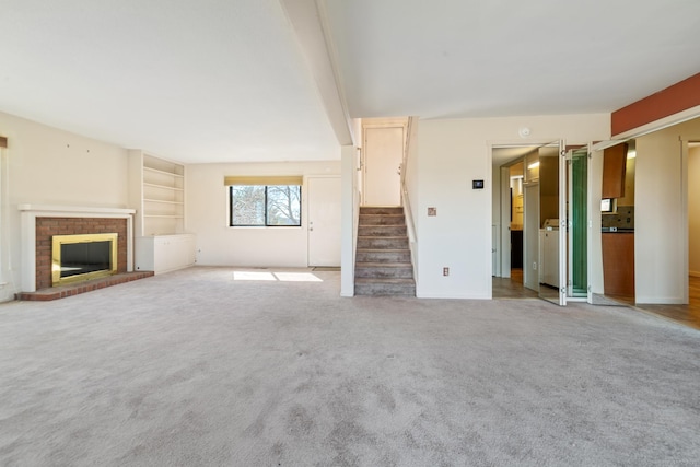 unfurnished living room with a fireplace, light carpet, and stairs