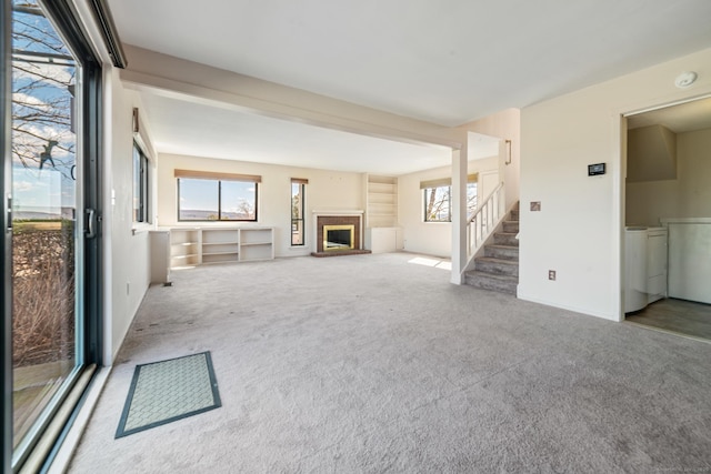unfurnished living room featuring independent washer and dryer, stairs, carpet, and a brick fireplace