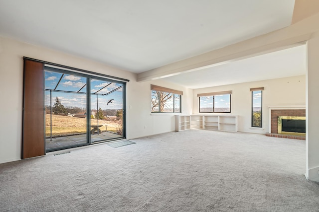 unfurnished living room with baseboards, a fireplace, visible vents, and carpet