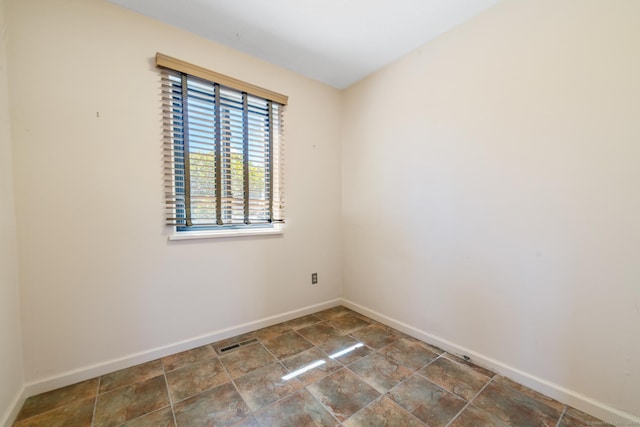empty room with baseboards, visible vents, and stone finish flooring