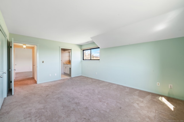 unfurnished bedroom with baseboards, ensuite bath, and light colored carpet