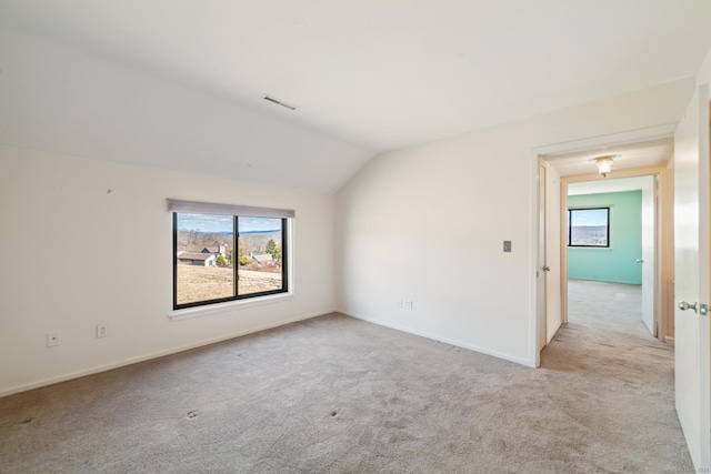 spare room featuring carpet, baseboards, vaulted ceiling, and visible vents