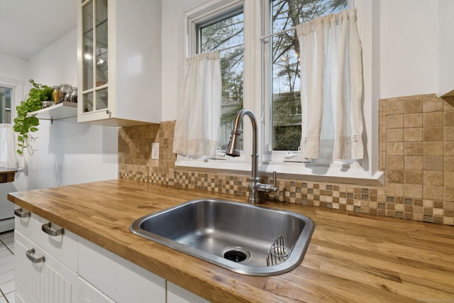 8 Lyle Ct Unit J, Farmington, CT 06032 - kitchen view of wood counters, a sink, white cabinetry, glass insert cabinets, and decorative backsplash