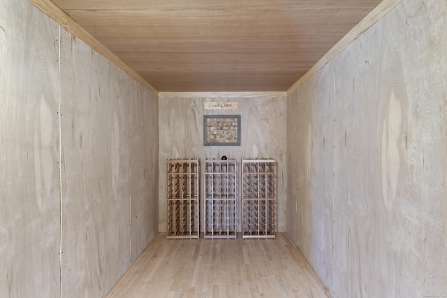 wine cellar with crown molding, wooden ceiling, and wood finished floors