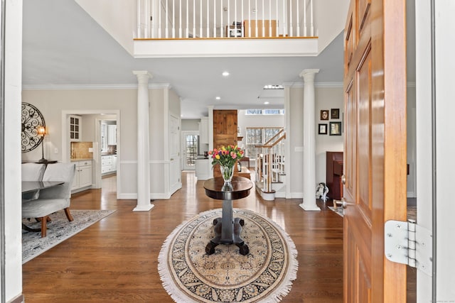 entrance foyer with baseboards, ornamental molding, stairs, decorative columns, and wood finished floors