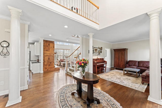 entryway featuring decorative columns, visible vents, ornamental molding, and wood finished floors