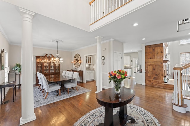 entrance foyer with ornate columns, ornamental molding, and wood finished floors