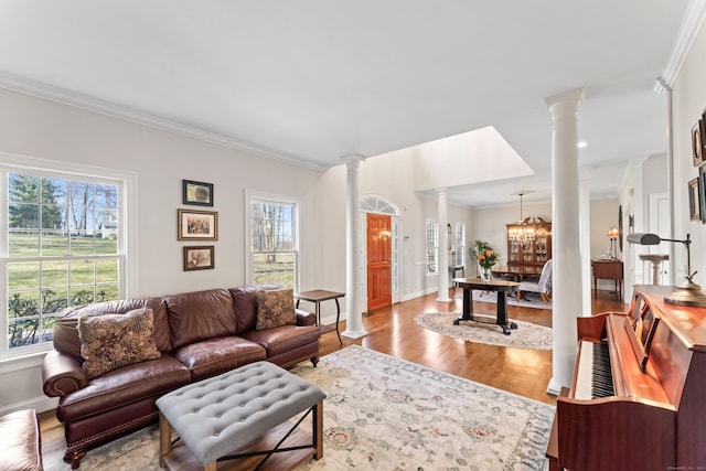 living room featuring ornate columns, wood finished floors, crown molding, and baseboards