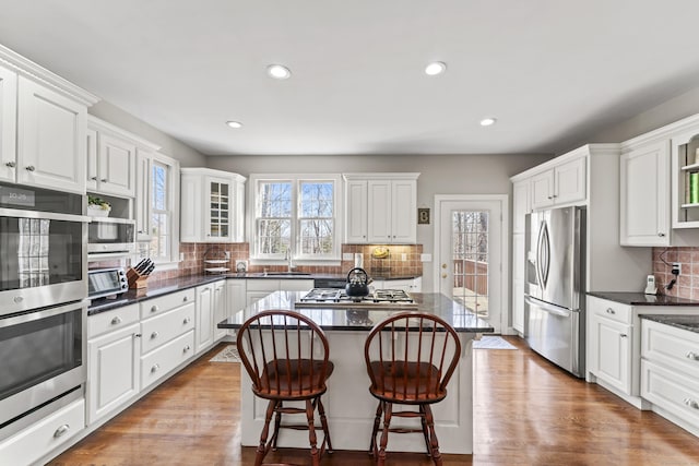 kitchen featuring wood finished floors, a sink, white cabinetry, and stainless steel appliances