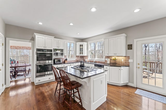 kitchen with stainless steel appliances, dark wood-type flooring, white cabinets, and a kitchen breakfast bar