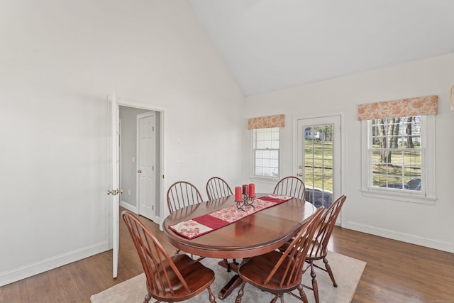 dining space with high vaulted ceiling, baseboards, and wood finished floors