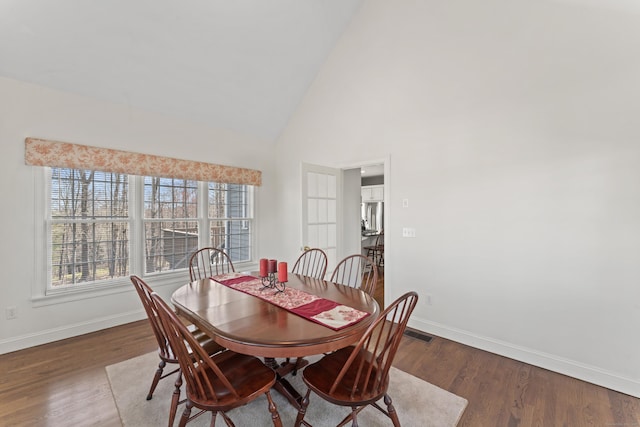 dining area with baseboards, high vaulted ceiling, and wood finished floors