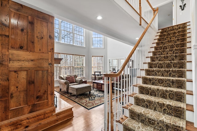 stairway with wood finished floors, a towering ceiling, and recessed lighting