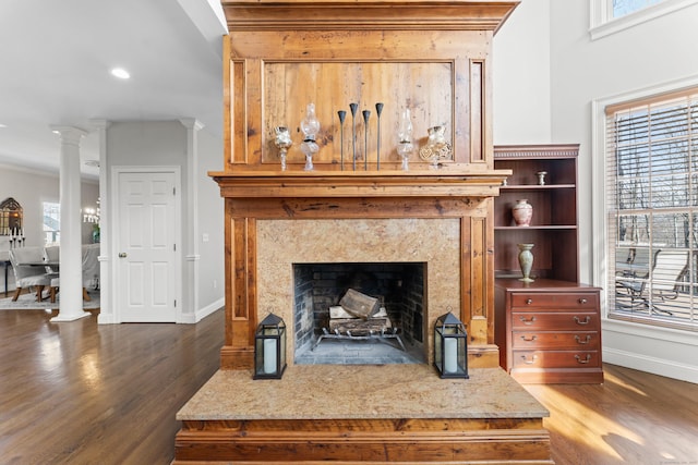 living room featuring a high end fireplace, ornate columns, baseboards, and wood finished floors