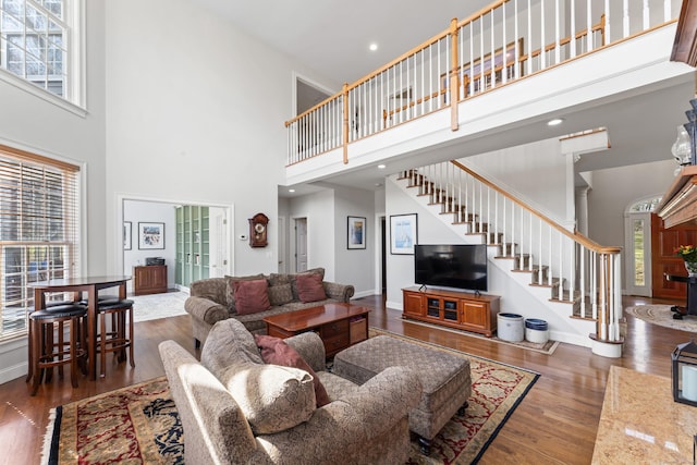 living room featuring a wealth of natural light, stairs, baseboards, and wood finished floors