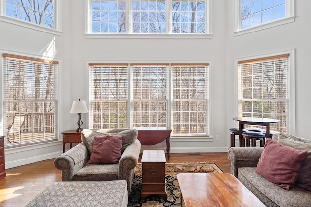 living area featuring a high ceiling, baseboards, and wood finished floors