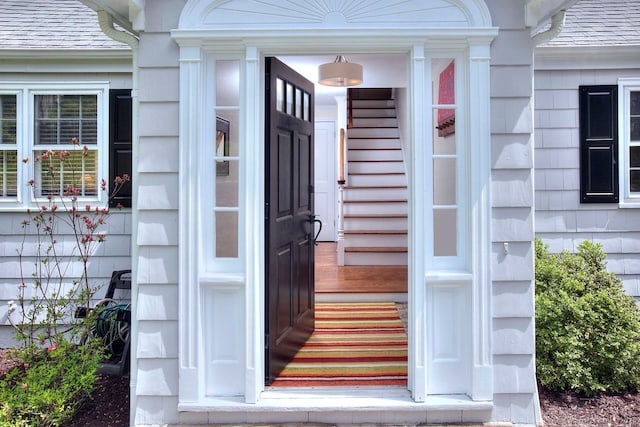entrance to property featuring roof with shingles