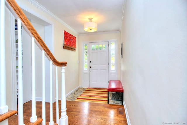 foyer entrance with wood finished floors, stairway, baseboards, visible vents, and ornamental molding