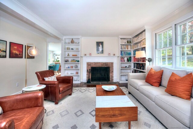 living area with ornamental molding, a brick fireplace, and built in features