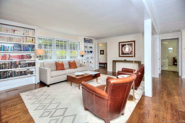 living room with ornamental molding, visible vents, built in features, and wood finished floors