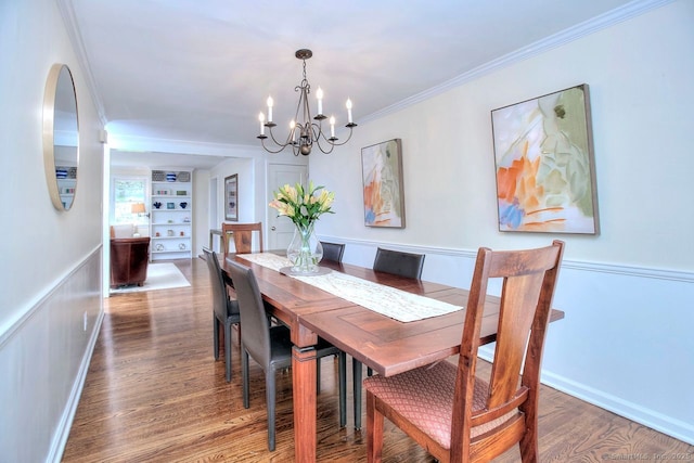 dining area with wood finished floors, ornamental molding, built in shelves, a chandelier, and baseboards