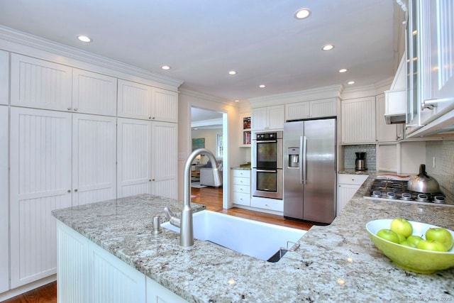 kitchen featuring tasteful backsplash, ornamental molding, light wood-style floors, white cabinets, and appliances with stainless steel finishes