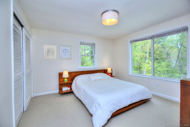 carpeted bedroom featuring a closet and baseboards