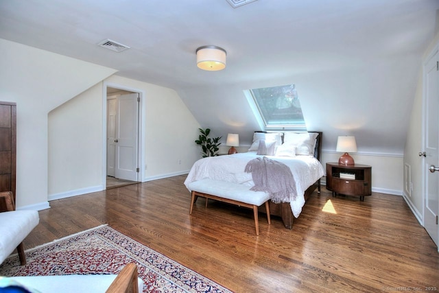 bedroom featuring vaulted ceiling with skylight, baseboards, visible vents, and wood finished floors