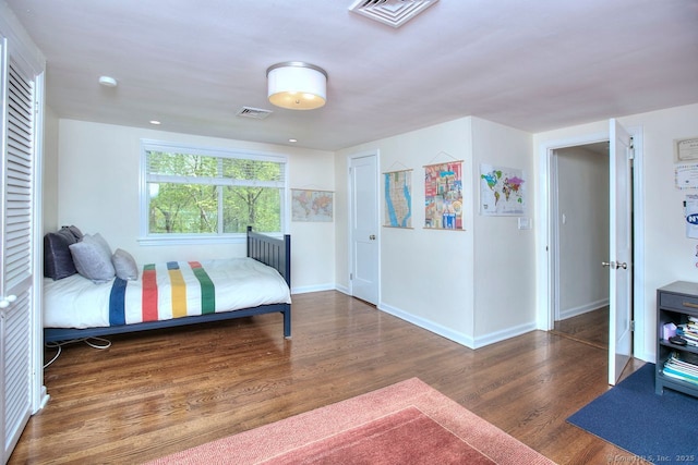 bedroom with baseboards, visible vents, and wood finished floors