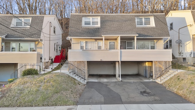 view of front of house with roof with shingles and driveway