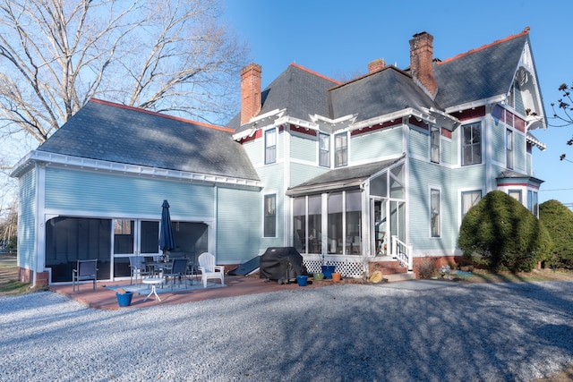 1063 Main St, South Windsor, CT 06074 - rear view of property featuring a sunroom, a patio area, entry steps, a chimney, and roof with shingles