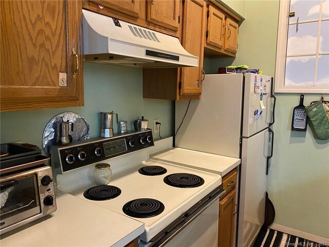 kitchen featuring electric stove, light countertops, brown cabinets, and under cabinet range hood