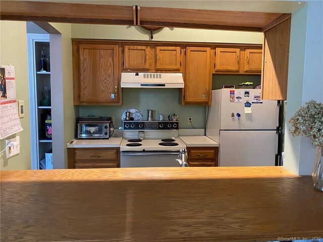 kitchen with light countertops, a toaster, white appliances, brown cabinets, and under cabinet range hood