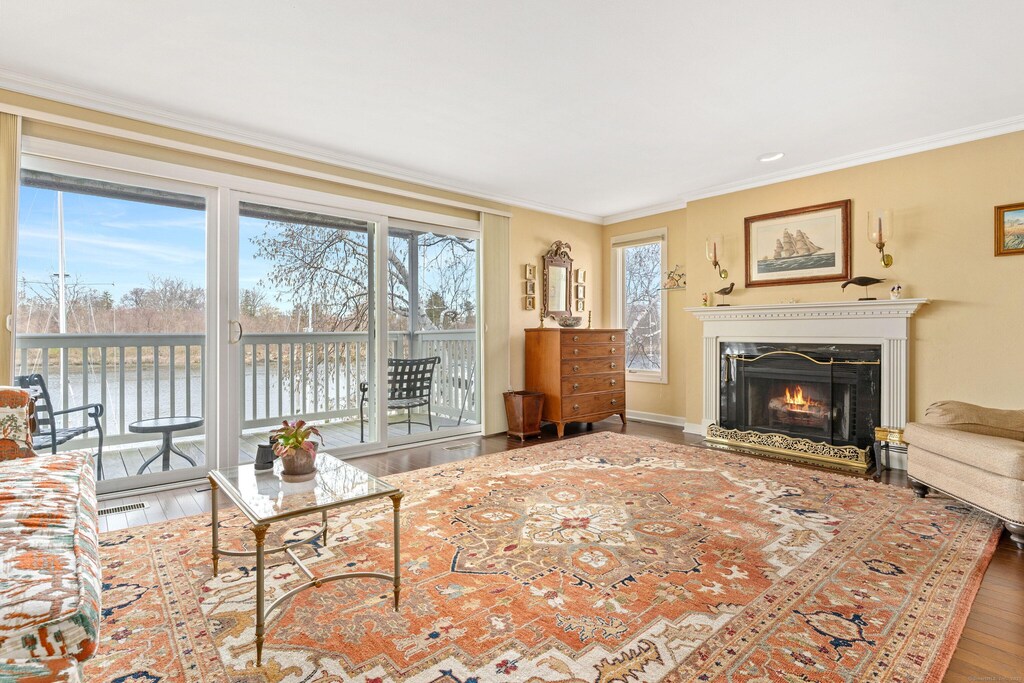 123 Harbor Dr Apt 411, Stamford, CT 06902 - living room featuring a water view, a lit fireplace, ornamental molding, and wood finished floors