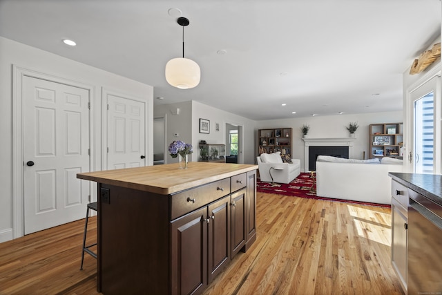 169 High Meadow Ln, Groton, CT 06355 - kitchen with butcher block countertops, light wood-style flooring, a kitchen breakfast bar, dark brown cabinets, and decorative light fixtures