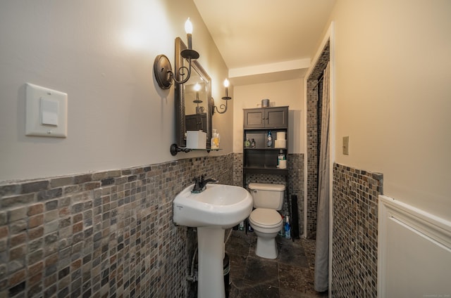 125 Northford Rd, Branford, CT 06405 - bathroom with stone tile floors, a wainscoted wall, toilet, and tile walls