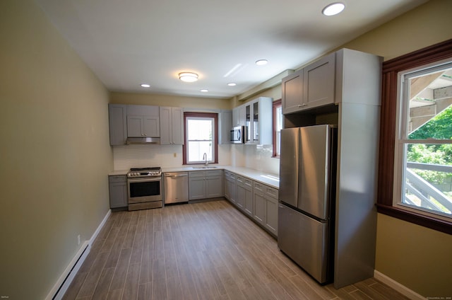 93 Broad St, Norwich, CT 06360 - kitchen featuring stainless steel appliances, gray cabinetry, a sink, wood finished floors, and decorative backsplash