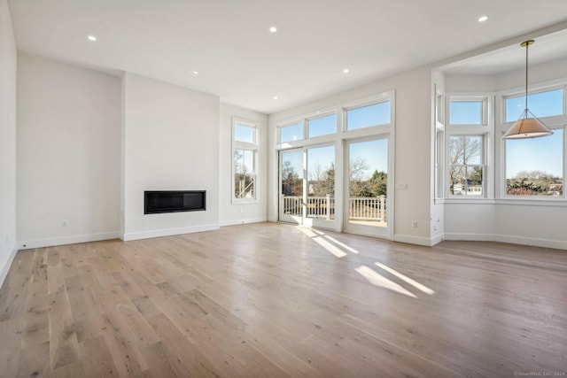 7 Egret Rd, Stonington, CT 06355 - unfurnished living room with healthy amount of natural light, light wood-type flooring, a glass covered fireplace, and recessed lighting