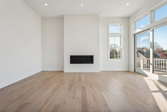 7 Egret Rd, Stonington, CT 06355 - unfurnished living room with light wood-type flooring, a glass covered fireplace, and recessed lighting