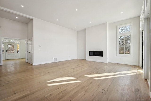7 Egret Rd, Stonington, CT 06355 - unfurnished living room with a glass covered fireplace, light wood finished floors, recessed lighting, and a high ceiling