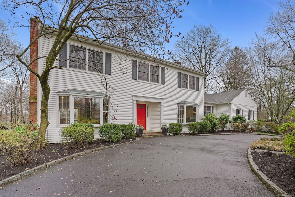 colonial home with a chimney and driveway