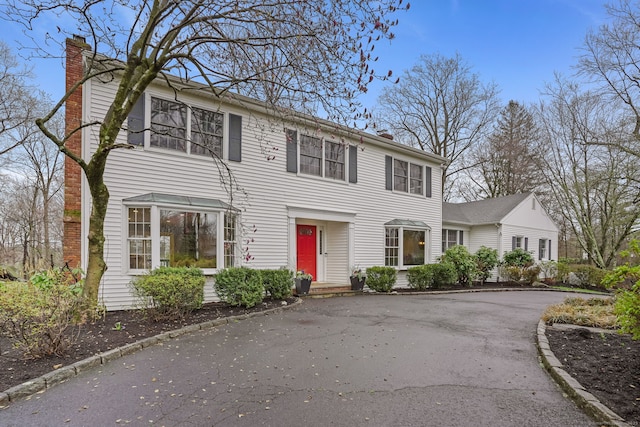 colonial home with a chimney and driveway