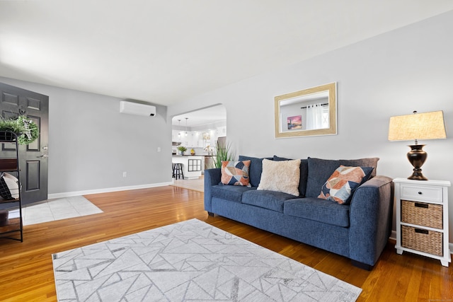 8 Dean Rd, East Lyme, CT 06333 - living area featuring an AC wall unit, wood finished floors, arched walkways, and baseboards