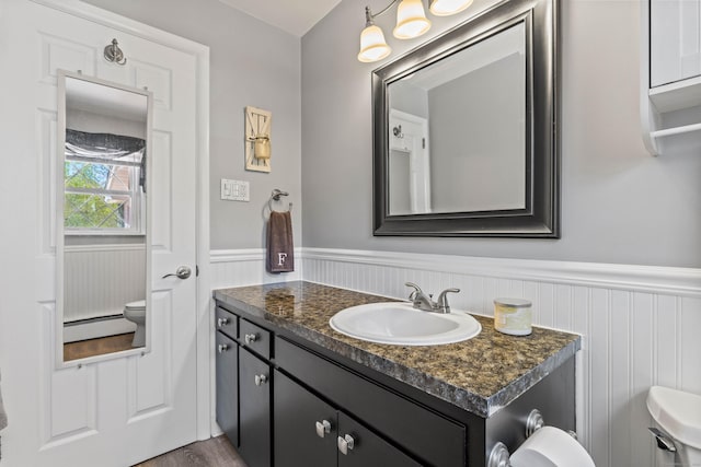 8 Dean Rd, East Lyme, CT 06333 - bathroom featuring a wainscoted wall, toilet, vanity, a baseboard radiator, and wood finished floors