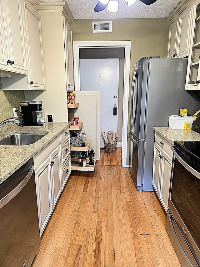 374 Heritage Vlg Unit C, Southbury, CT 06488 - kitchen featuring appliances with stainless steel finishes, a sink, light wood-type flooring, a ceiling fan, and light stone countertops