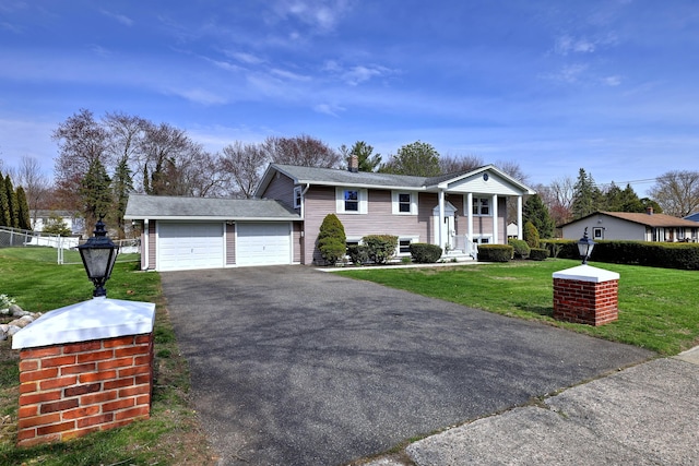 view of front of property with a front yard, driveway, a chimney, an attached garage, and fence
