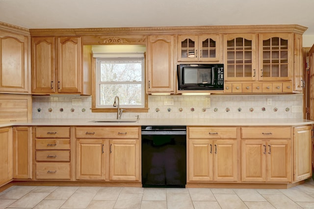 kitchen featuring black appliances, glass insert cabinets, light countertops, and a sink
