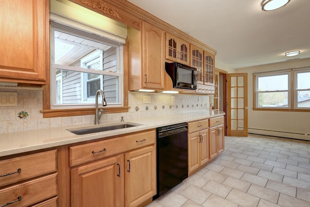 kitchen with tasteful backsplash, glass insert cabinets, a baseboard heating unit, black appliances, and a sink